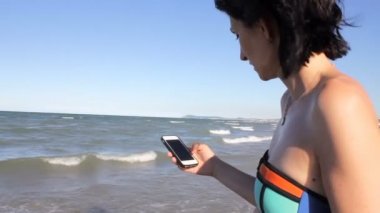 Bikini sms manifatura app plajda akıllı telefon kullanarak kadında. Açık havada smartphone kullanarak eller closeup. Mobil cep telefonu kapat.