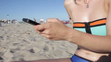 Bikini sms manifatura app plajda akıllı telefon kullanarak kadında. Açık havada smartphone kullanarak eller closeup. Mobil cep telefonu kapat.