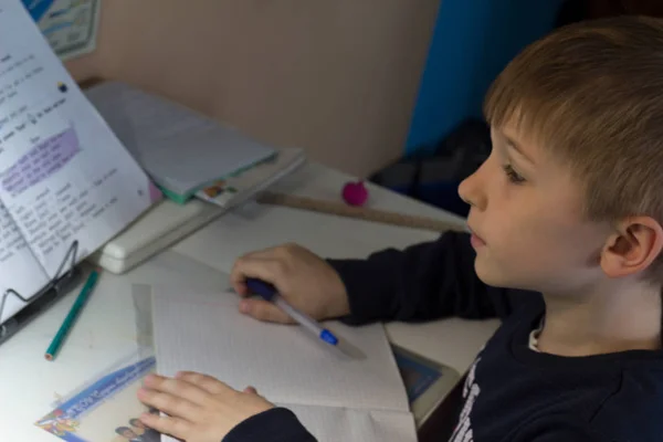 Niño con lápiz escribiendo palabras en inglés a mano en papel blanco tradicional de bloc de notas . —  Fotos de Stock