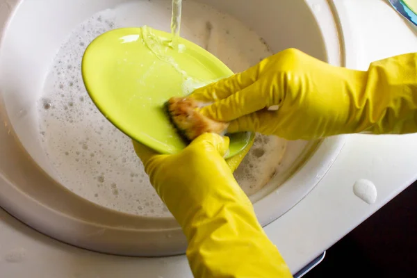 Washing dishes in yellow gloves