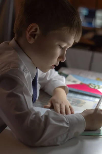 Éducation à domicile. Travail à domicile après l'école. Garçon avec stylo écrire des mots anglais à la main sur papier bloc-notes blanc traditionnel . — Photo