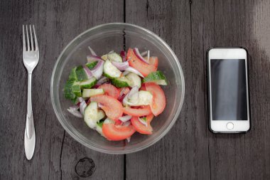 Diyet sebze salatası soğan, salatalık, domates ve cep telefonu. Üstten Görünüm