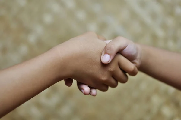 İki çocuk el sıkışıyor. Barış işareti ya da anlaşma için el hareketi.