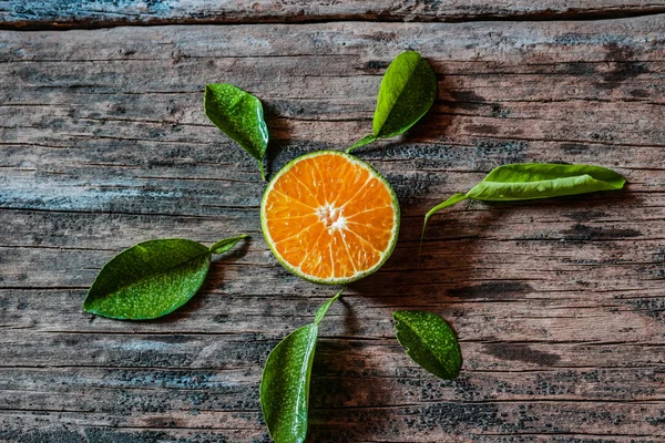 Köy ahşap masasında yaprakları olan bir dilim taze yerel portakal. Endonezya 'da bu meyveye jeruk denir..