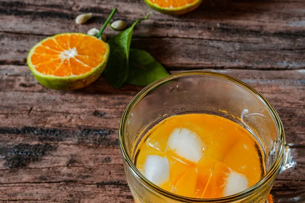 Bir bardak portakal suyu eski ahşap bir masada, taze yerel portakal dilimleri ve yapraklarıyla tamamlanmış. Endonezya 'da buna 