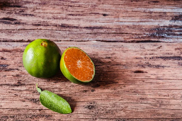 Köy ahşap masasında yaprakları olan taze yerel portakallar. Endonezya 'da bu meyveye jeruk denir..