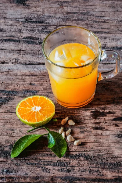Bir bardak portakal suyu eski ahşap bir masada, taze yerel portakal dilimleri ve yapraklarıyla tamamlanmış. Endonezya 'da buna 