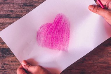 Heart symbol on white paper created from pink pencil