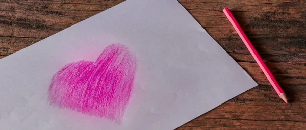 Heart symbol on white paper created from pink pencil