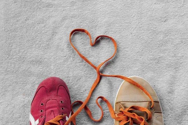 Cordones de zapatos que unen un par de zapatillas de deporte se forman en un corazón — Foto de Stock