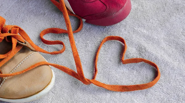 Shoelaces that unite a pair of sneakers are formed into a heart 