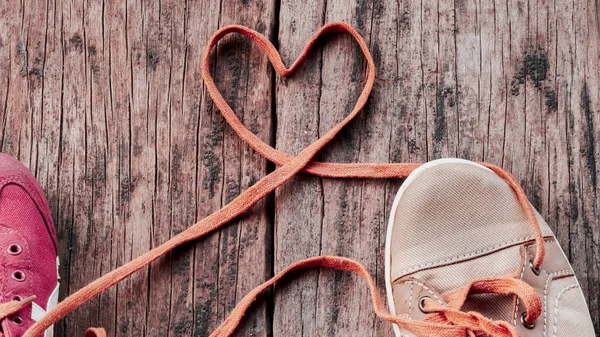 Shoelaces that unite a pair of sneakers are formed into a heart 