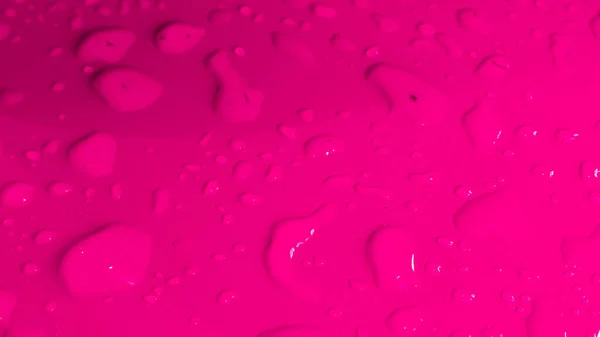 雨はピンクの光沢のある表面に落ちる 水滴の背景 — ストック写真