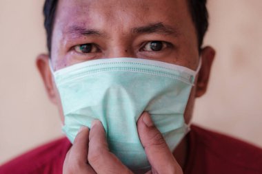 Endonezyalı adam kendini covid-19 salgınından korumak için tıbbi maske takıyor.