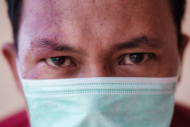 Kendini virüsten korumak için tıbbi maske takan Asyalı bir adam.