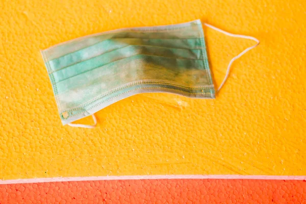 Sarı arka planda tıbbi yüz maskesi. Virüs hastalıklarında veya covid-19 ve filovirüs gibi salgınlarda kullanılmak üzere genel kişisel koruma ekipmanları.