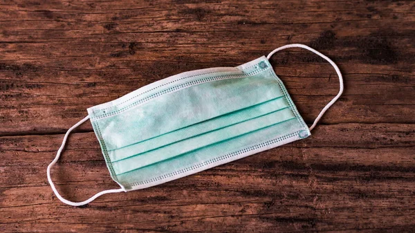 Tahta yüzeyde tıbbi yüz maskesi. Virüs hastalıklarında veya covid-19 ve filovirüs gibi salgınlarda kullanılmak üzere genel kişisel koruma ekipmanları.