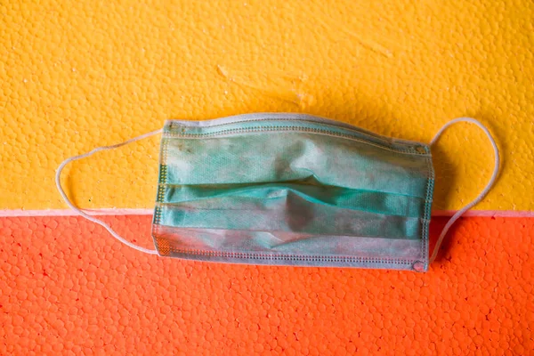 Sarı turuncu yüzeyde cerrahi maske. Virüs hastalıklarında veya covid-19 ve filovirüs gibi salgınlarda kullanılmak üzere genel kişisel koruma ekipmanları.