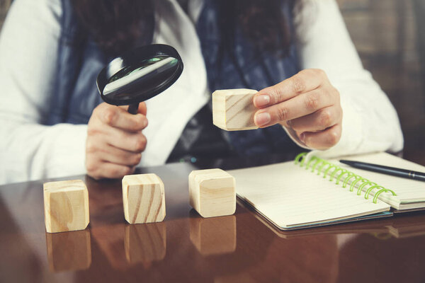 woman hand magnifier with wooden cubes