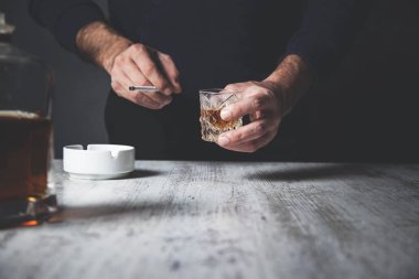 Üzgün adam elinde sigarayla viski