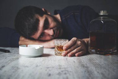 Üzgün adam elinde sigarayla viski