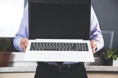 Genç iş adamı beyaz bilgisayarı tutuyor.