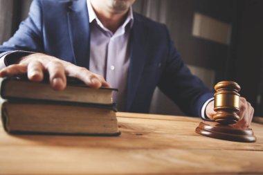 Masasında kitap olan bir adam el yargıcı.