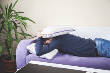 Evdeki kanepede uyuyan genç adam.