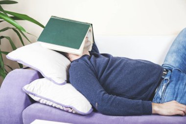 Kanepede uzanmış uyuyan adamın yüzü kitabı.