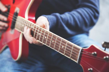 Gri arka planda gitar çalan bir adam.