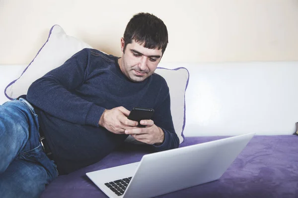man hand phone with notebook sitting on sofa