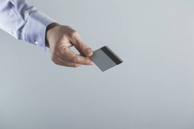 Gri arka planda erkek eli kredi kartı