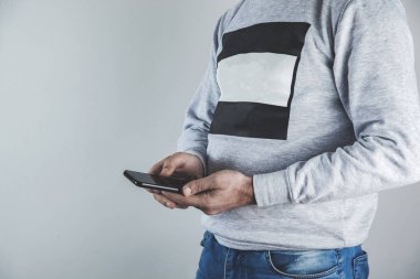 Gri arka planda telefonu tutan adam.