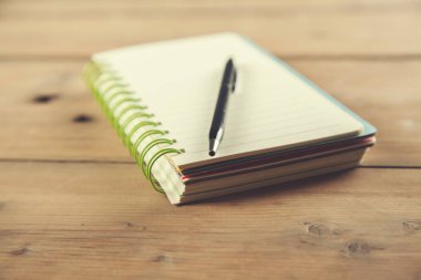 Ahşap masadaki not defterine bir kalem.