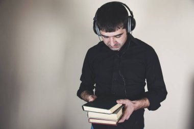 Elinde kitaplarla kulaklık tutan genç adam.