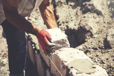 Adam duvar örüyor.