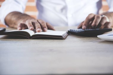Masasında not defteri olan bir adam el hesap makinesi.