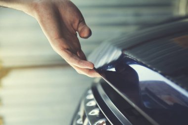 Adam elini arabanın kaputuna koydu.