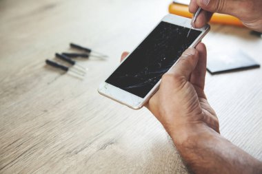 İşçi eli kırık telefon masanın üstünde.