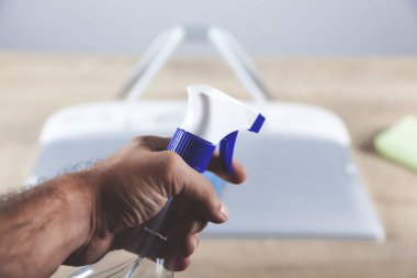 Ahşap masadaki bilgisayarı temizleyen adam.