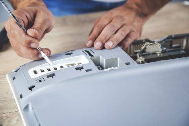 Genç işçi masadaki bilgisayarı tamir ediyor.