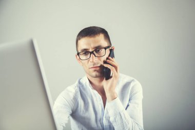 İşçi büro masasında telefonla konuşuyor.