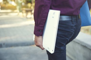 Adam doğada beyaz bilgisayarı tutuyor.