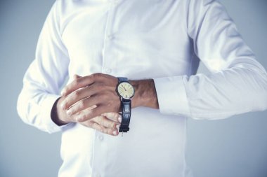 Genç iş adamı gri arka planda el gözetimi yapıyor.