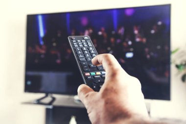 TV arka planı olan bir adam el kumandası