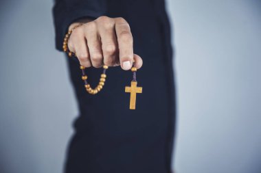 Dua eden adam gri duvar arkasında el pençe divan duruyor.