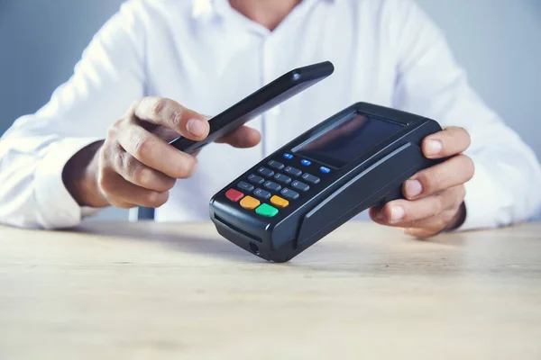 Masasında ödeme terminali olan bir adam cep telefonu.