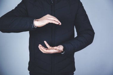 Gri arka planda eli boş bir adam.