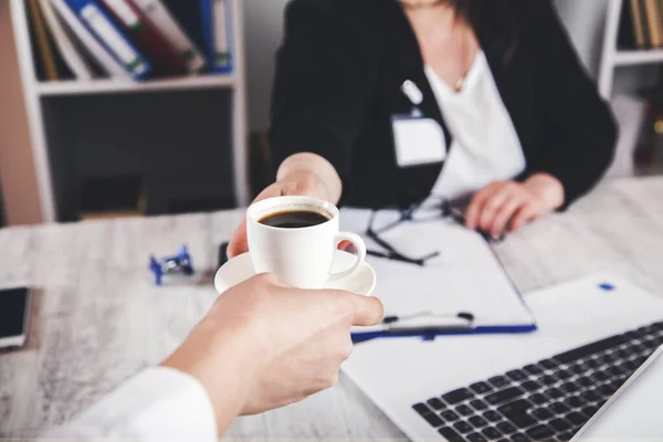 woman boss with worker hand coffee on desk