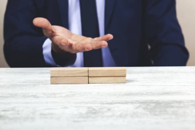 Kavramsal bir görüntüde, beyaz yansıtıcı bir masada, boş tahta küpleri için ellerini koruyucu bir şekilde tutan bir adam. Metnin için hazır. 